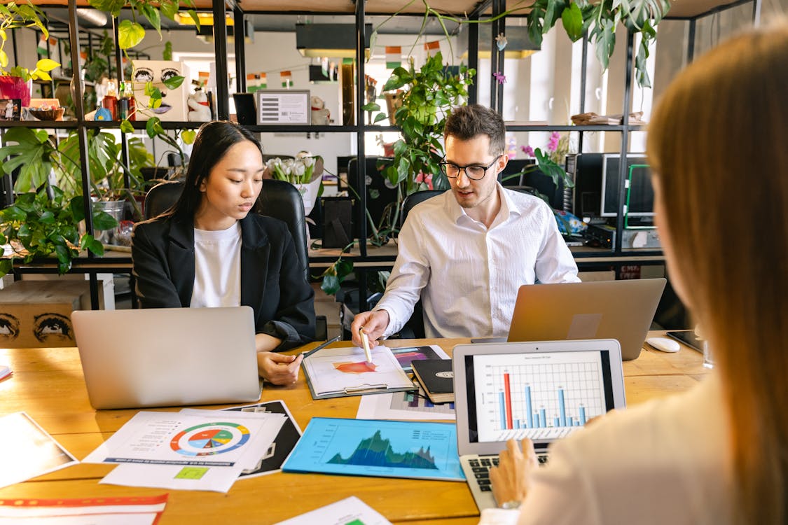 People collaborating around laptops and charts in a modern office